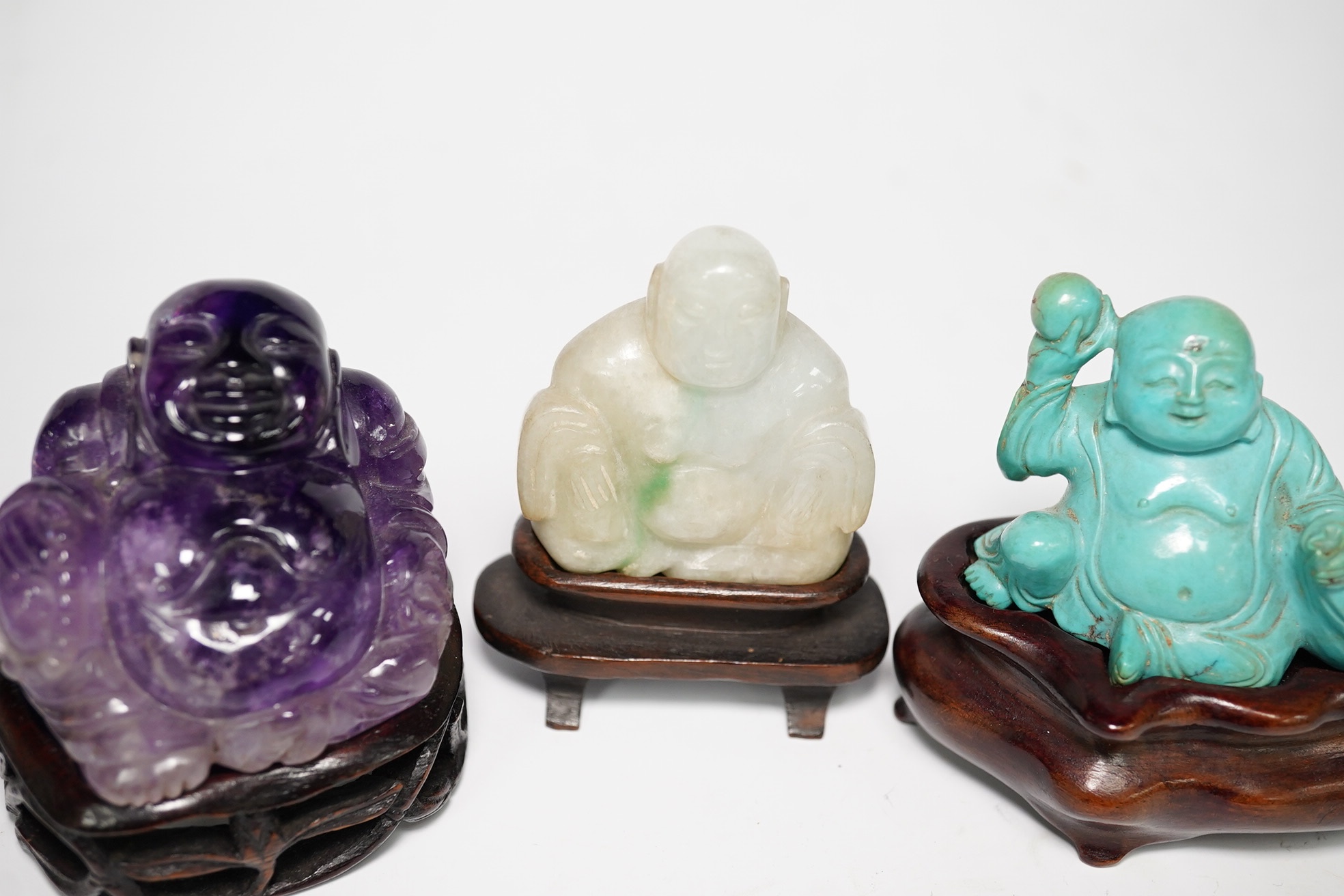 Three Chinese hardstone carvings of Budai, in jadeite, turquoise matrix and amethyst crystal, largest amethyst 4.5cm wide at base (3). Condition - good